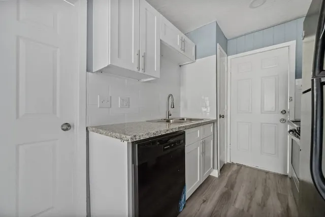 a kitchen with stainless steel appliances granite countertop a sink and cabinets with wooden floor