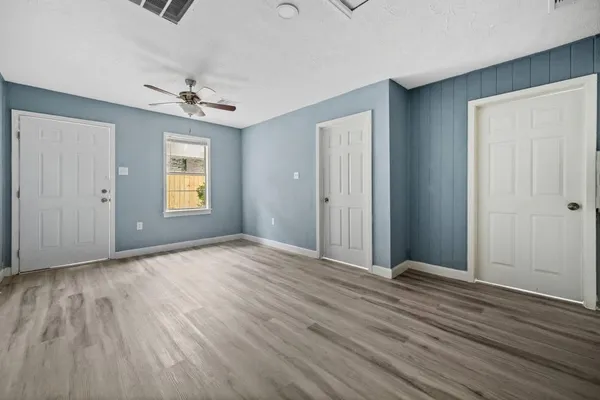 a view of empty room with wooden floor and fan