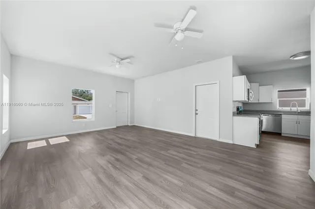 an empty room with wooden floor and a ceiling fan