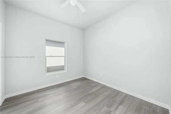 an empty room with wooden floor and a ceiling fan
