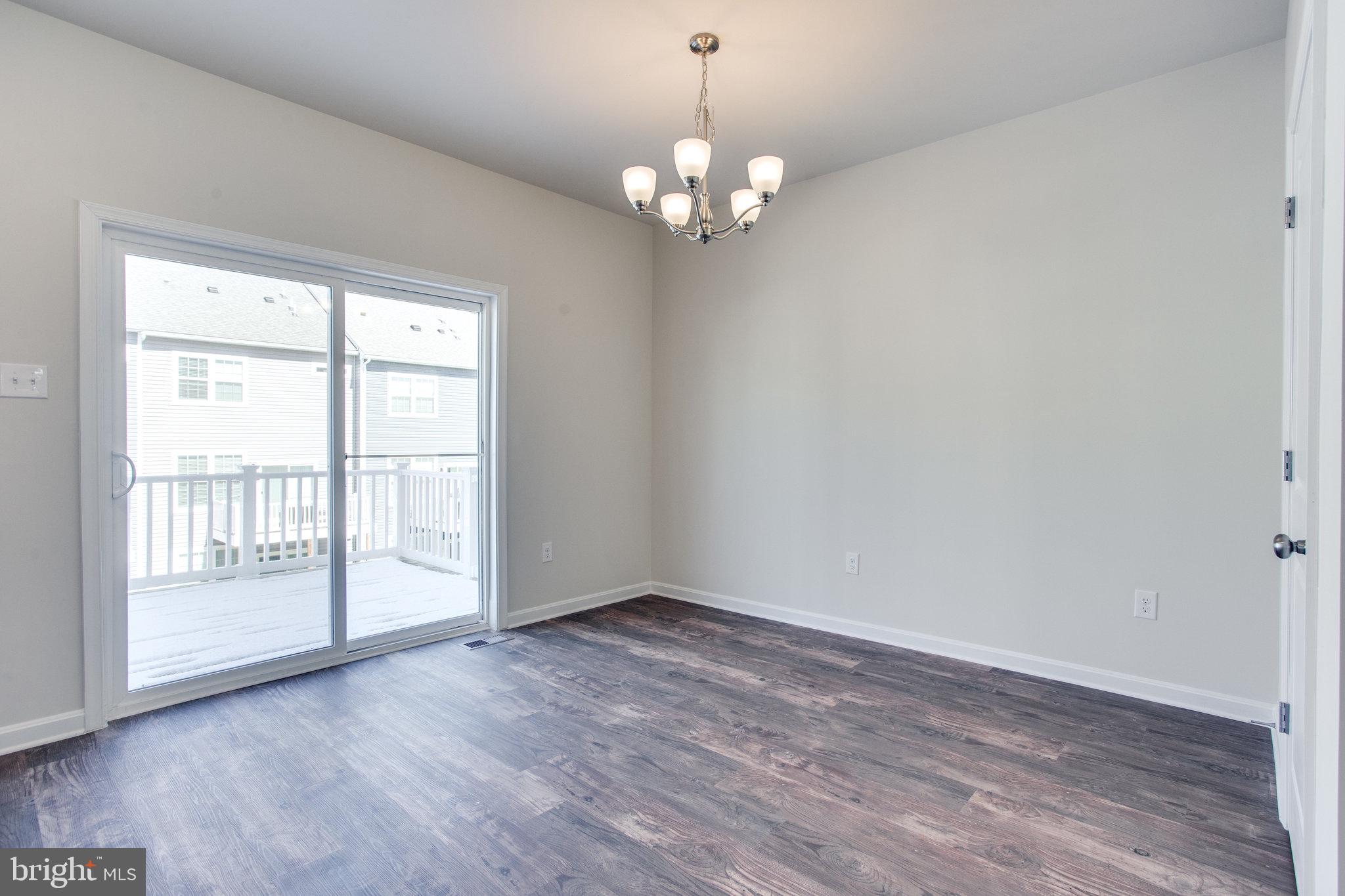 5039 MacDonough Place Frederick, MD 21703 - Photo 11 of 35 a view of an empty room with wooden floor and a window
