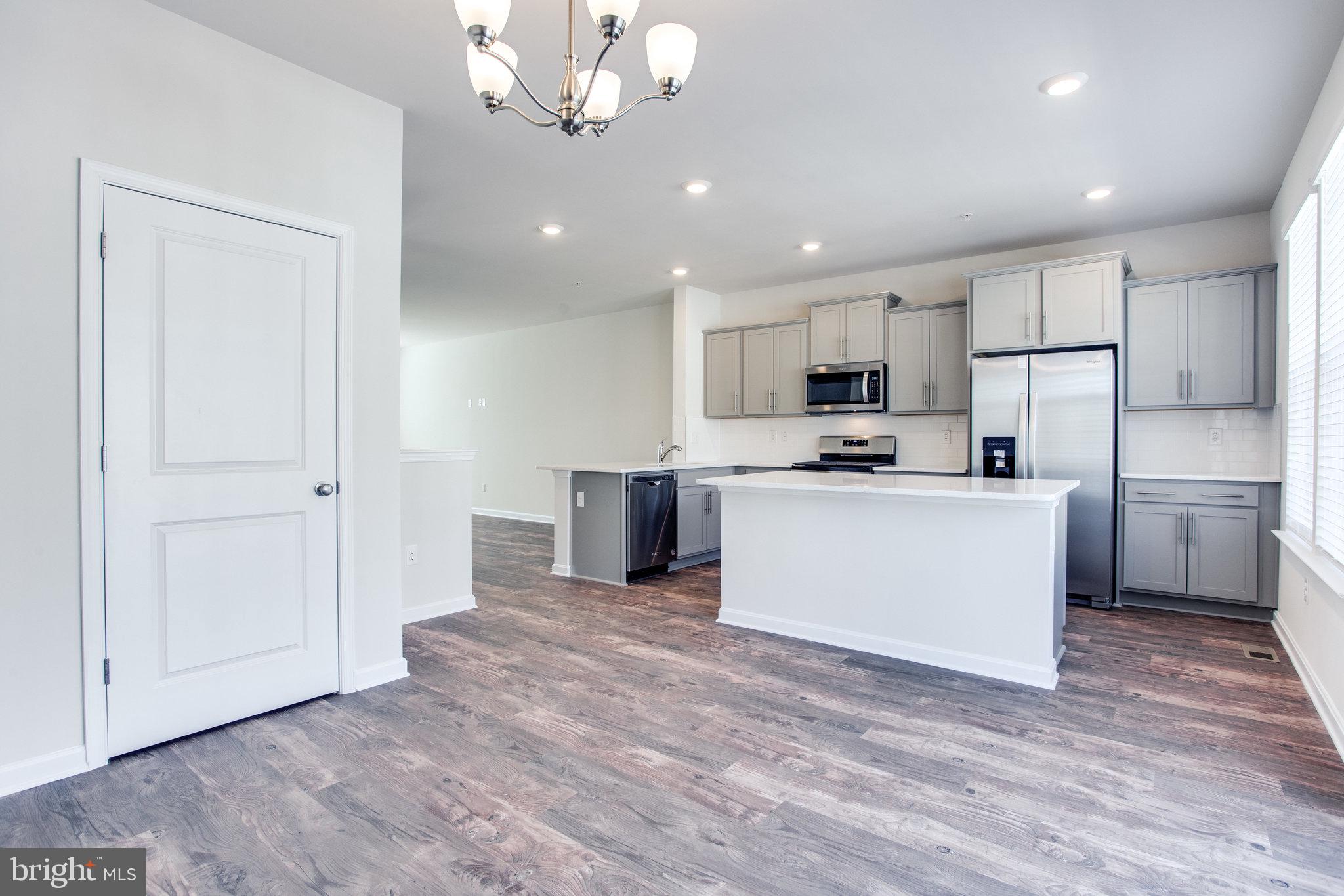 5039 MacDonough Place Frederick, MD 21703 - Photo 15 of 35 a kitchen with stainless steel appliances granite countertop a refrigerator a sink dishwasher a stove and white cabinets with wooden floor