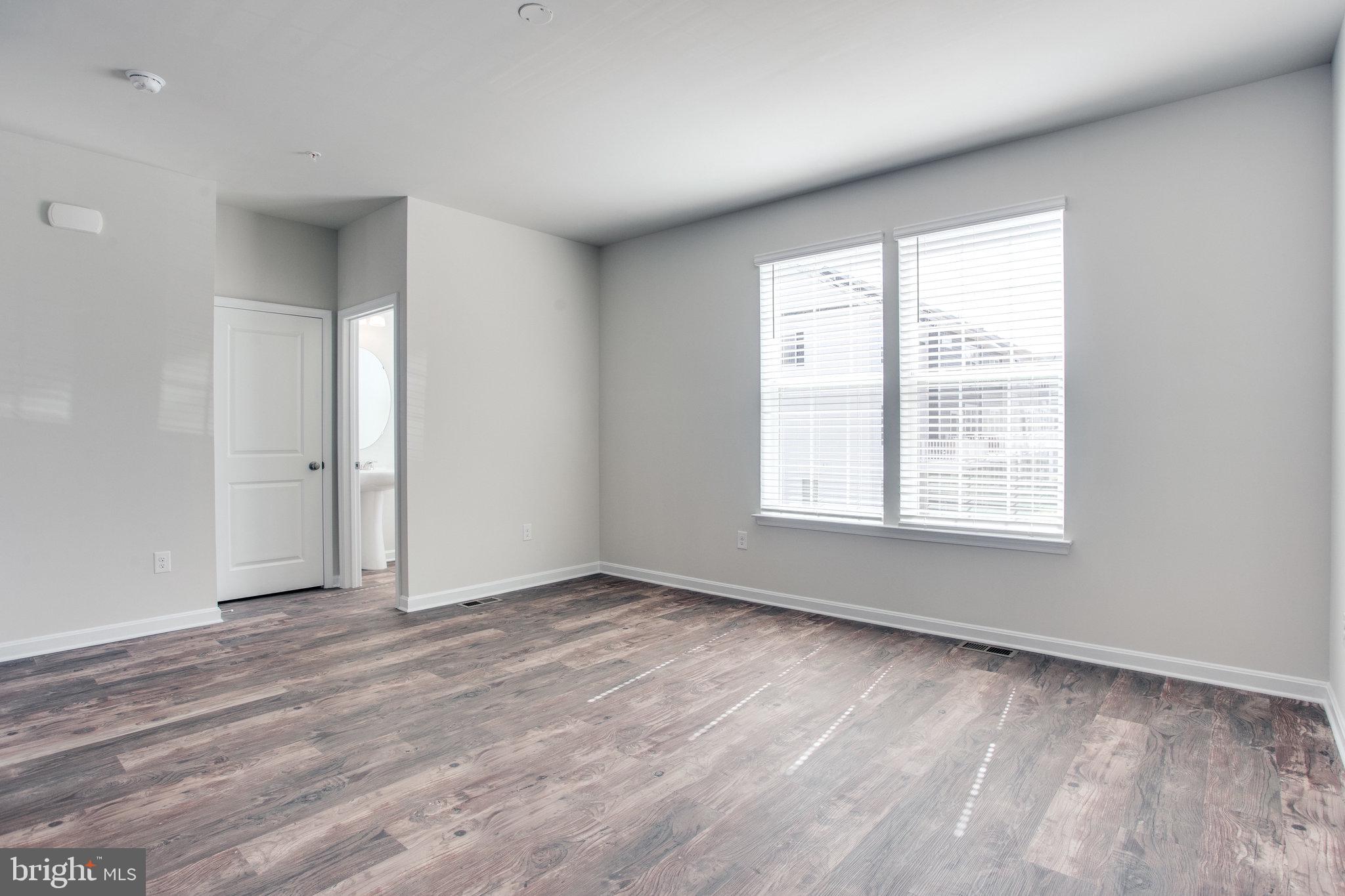 5039 MacDonough Place Frederick, MD 21703 - Photo 7 of 35 a view of an empty room with wooden floor and a window