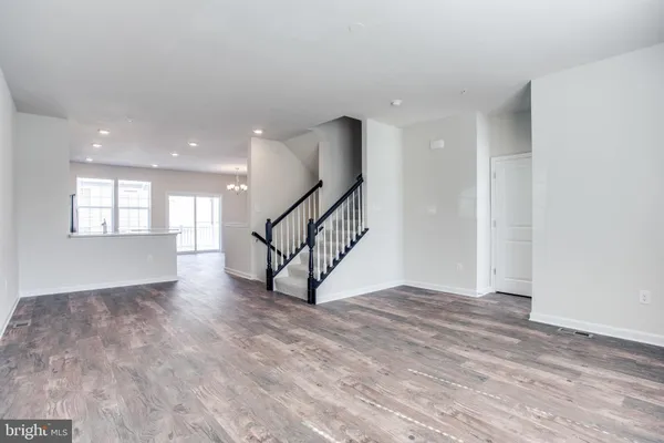 a view of an empty room with wooden floor and stairs