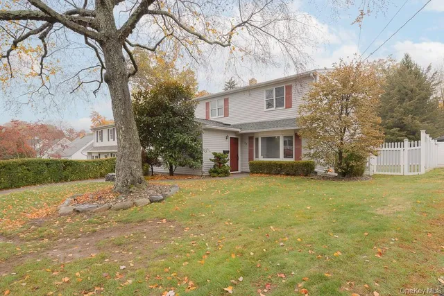 a view of a yard in front of a house with a large tree