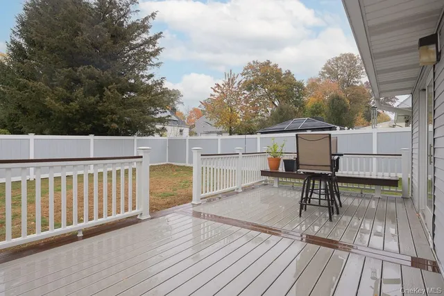 a view of a roof deck with table and chairs a barbeque with wooden floor and fence