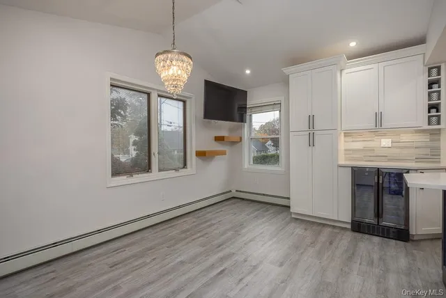 a view of an empty room with kitchen and window