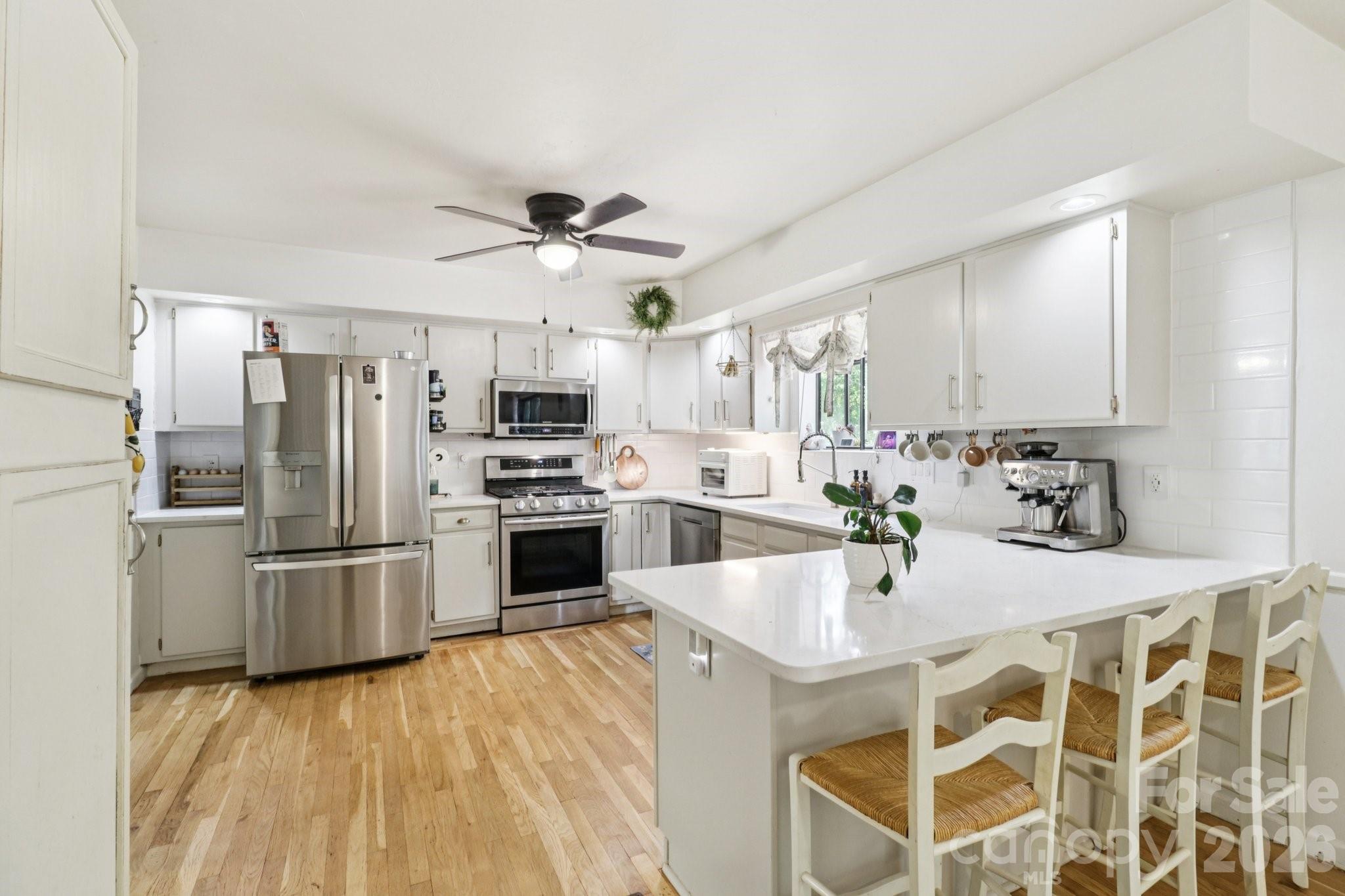 5483 Valley Run Street Hickory, NC 28601 - Photo 12 of 48 a kitchen with stainless steel appliances kitchen island granite countertop a refrigerator a stove a sink dishwasher and white cabinets with wooden floor