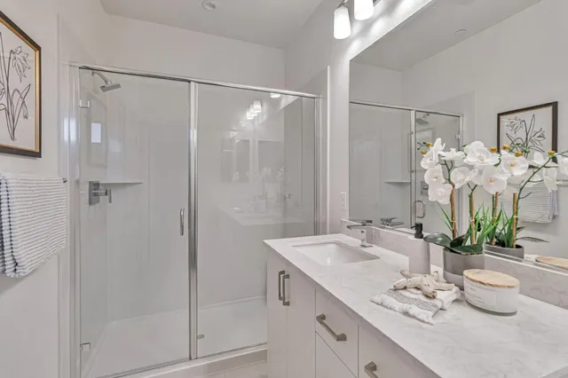 a bathroom with a shower sink vanity granite and a mirror
