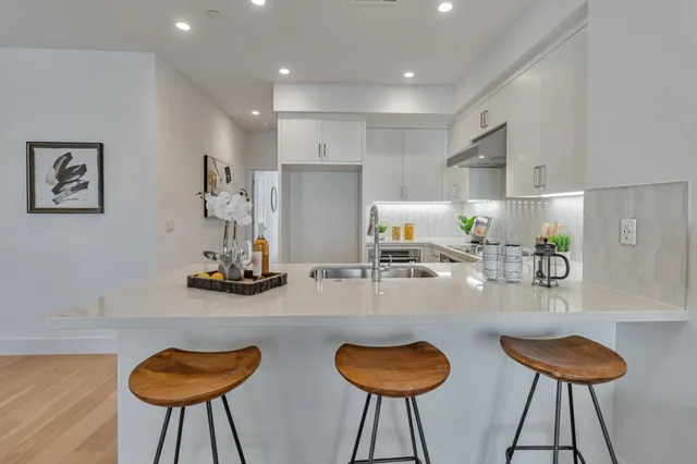 a kitchen with stainless steel appliances granite countertop a dining table chairs and a sink