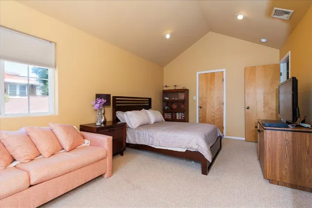 a spacious bedroom with a bed and a flat screen television
