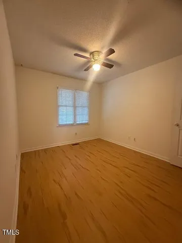 an empty room with a window and ceiling fan