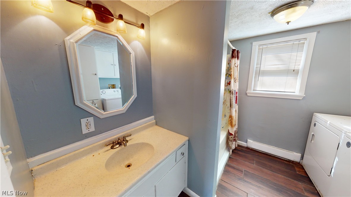6970 Bushnell Road Conneaut, OH 44030 - Photo 4 of 28 Bathroom featuring vanity, hardwood / wood-style flooring, washer and clothes dryer, and a textured ceiling