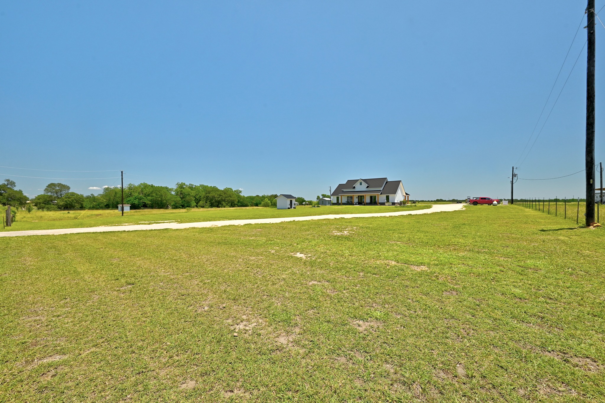 2889 Old McMahan Road Lockhart, TX 78644 - Photo 4 of 33 A charming farmhouse and detached shed sits nestled in an open, grassy field.