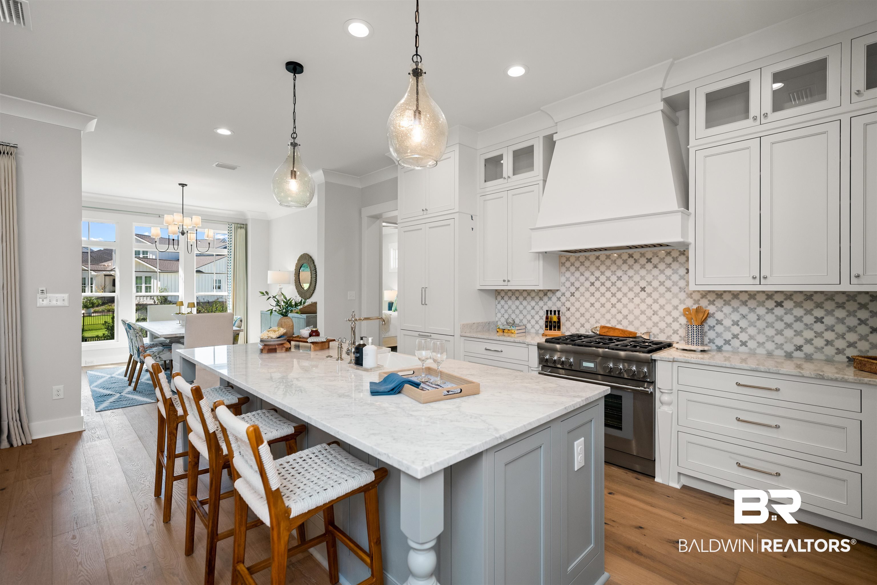 156 Hyacinth Street Fairhope, AL 36532 - Photo 11 of 61 Kitchen with tasteful backsplash, light stone countertops, pendant lighting, white cabinets, and crown molding