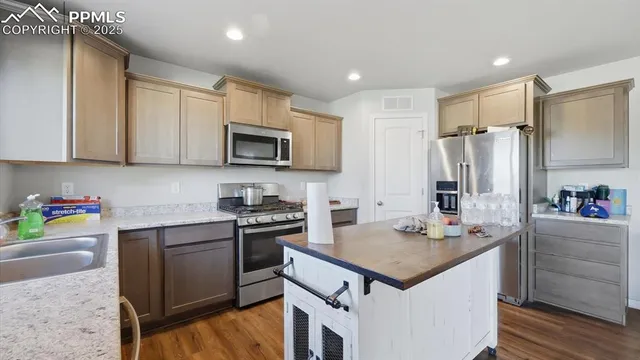 a kitchen with kitchen island granite countertop a sink appliances and cabinets