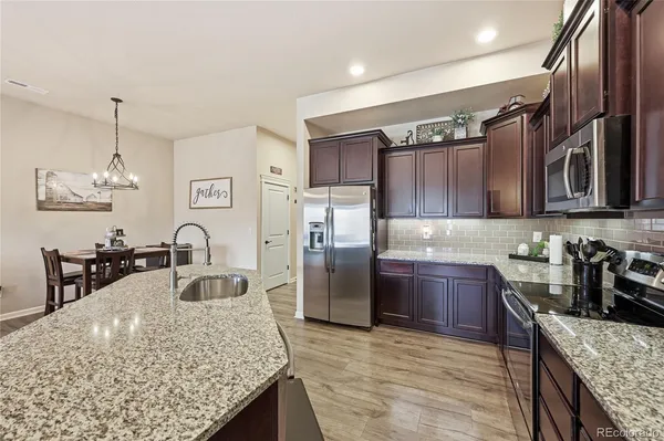 a living room with stainless steel appliances kitchen island granite countertop furniture a rug kitchen view and a chandelier