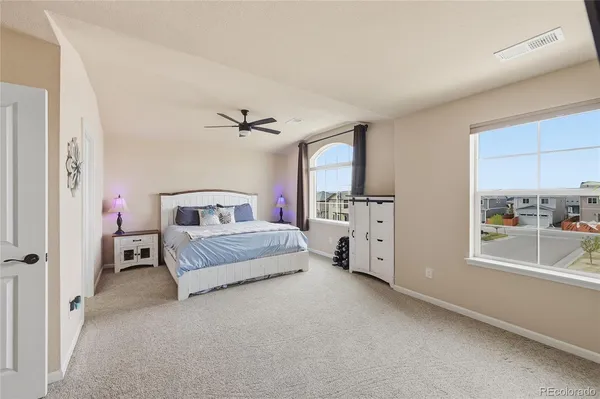 a spacious bedroom with a large bed a fireplace and a chandelier