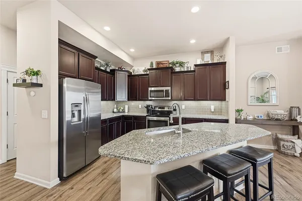 a kitchen with kitchen island granite countertop a sink stainless steel appliances and cabinets