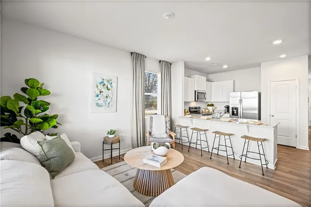 a living room with stainless steel appliances furniture a dining table and chairs