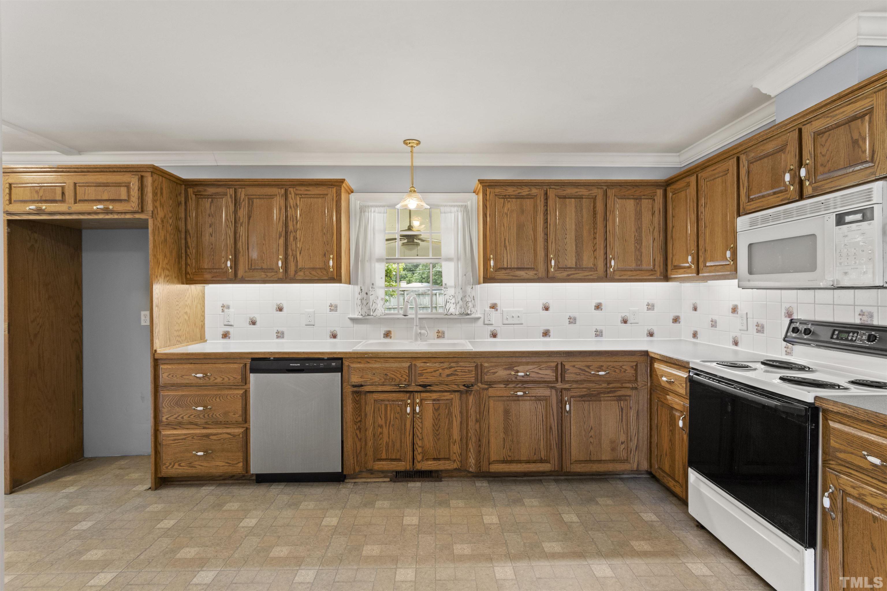 4811 Greenbrier Road Raleigh, NC 27603 - Photo 13 of 41 a kitchen with stainless steel appliances granite countertop a sink and dishwasher a stove top oven with wooden floor