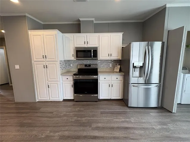a kitchen with white cabinets stainless steel appliances and a refrigerator