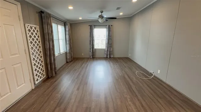 an empty room with wooden floor and windows