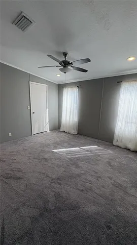 a view of an empty room with window and chandelier fan