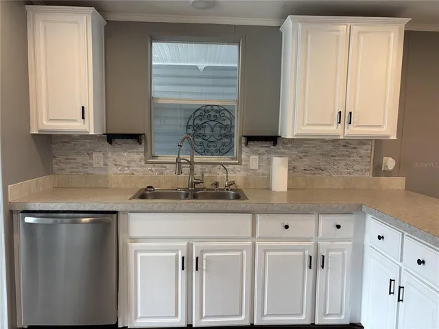 a kitchen with stainless steel appliances granite countertop a sink and a white cabinets