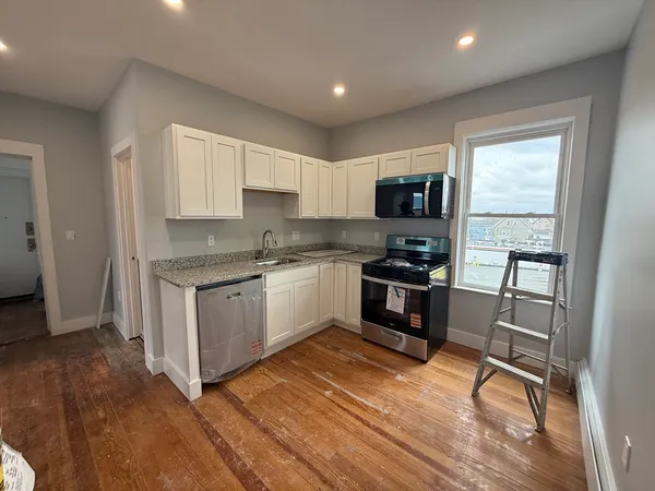 a kitchen with granite countertop a stove a sink and a refrigerator