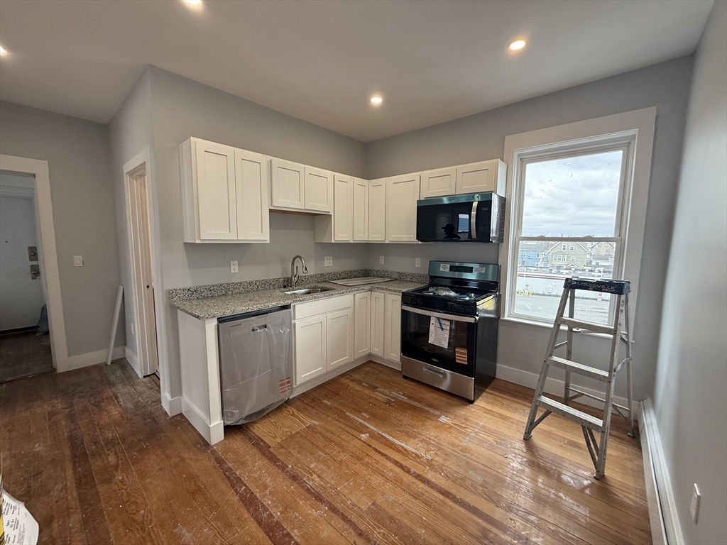 a kitchen with granite countertop a stove a sink and a refrigerator