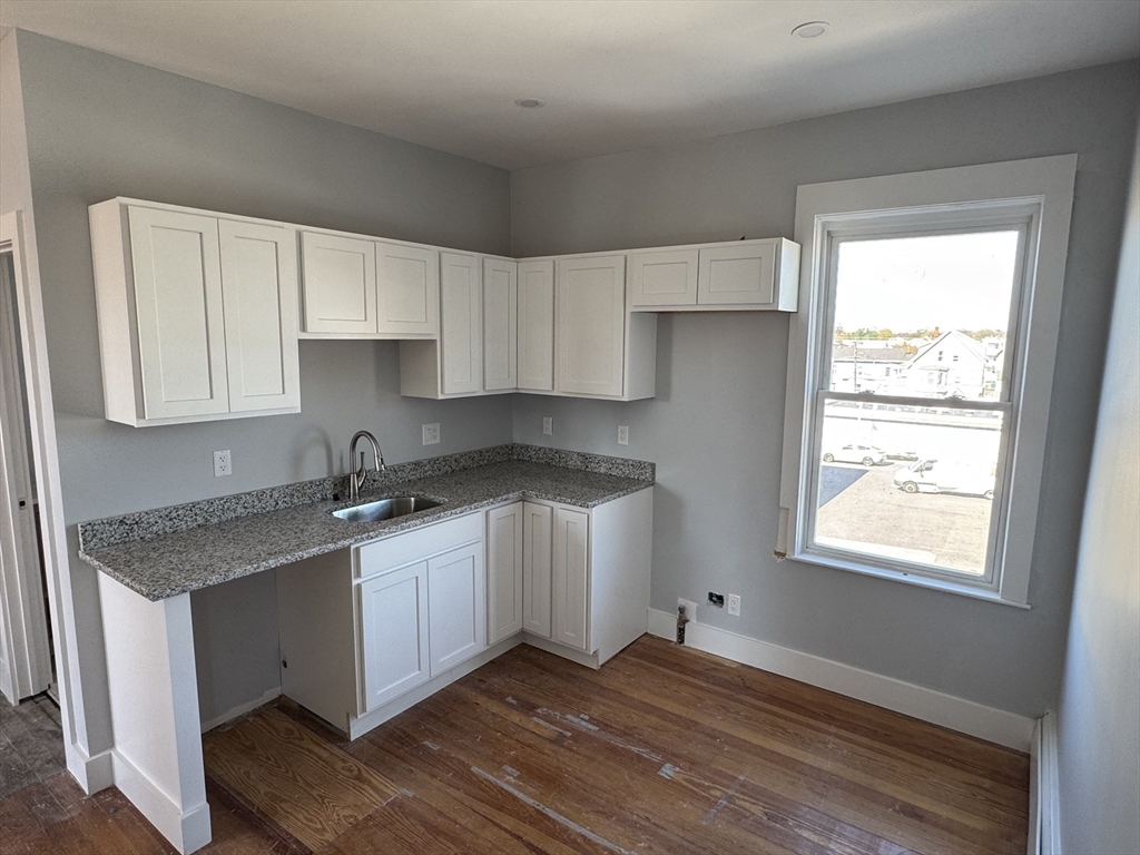 8 Carnes Street, Unit 2R Lynn, MA 01905 - Photo 2 of 15 a kitchen with granite countertop white cabinets and a window