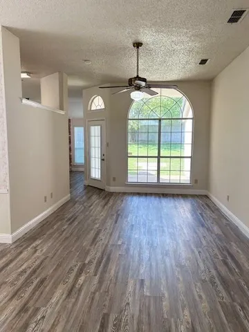 a view of empty room with wooden floor and fan