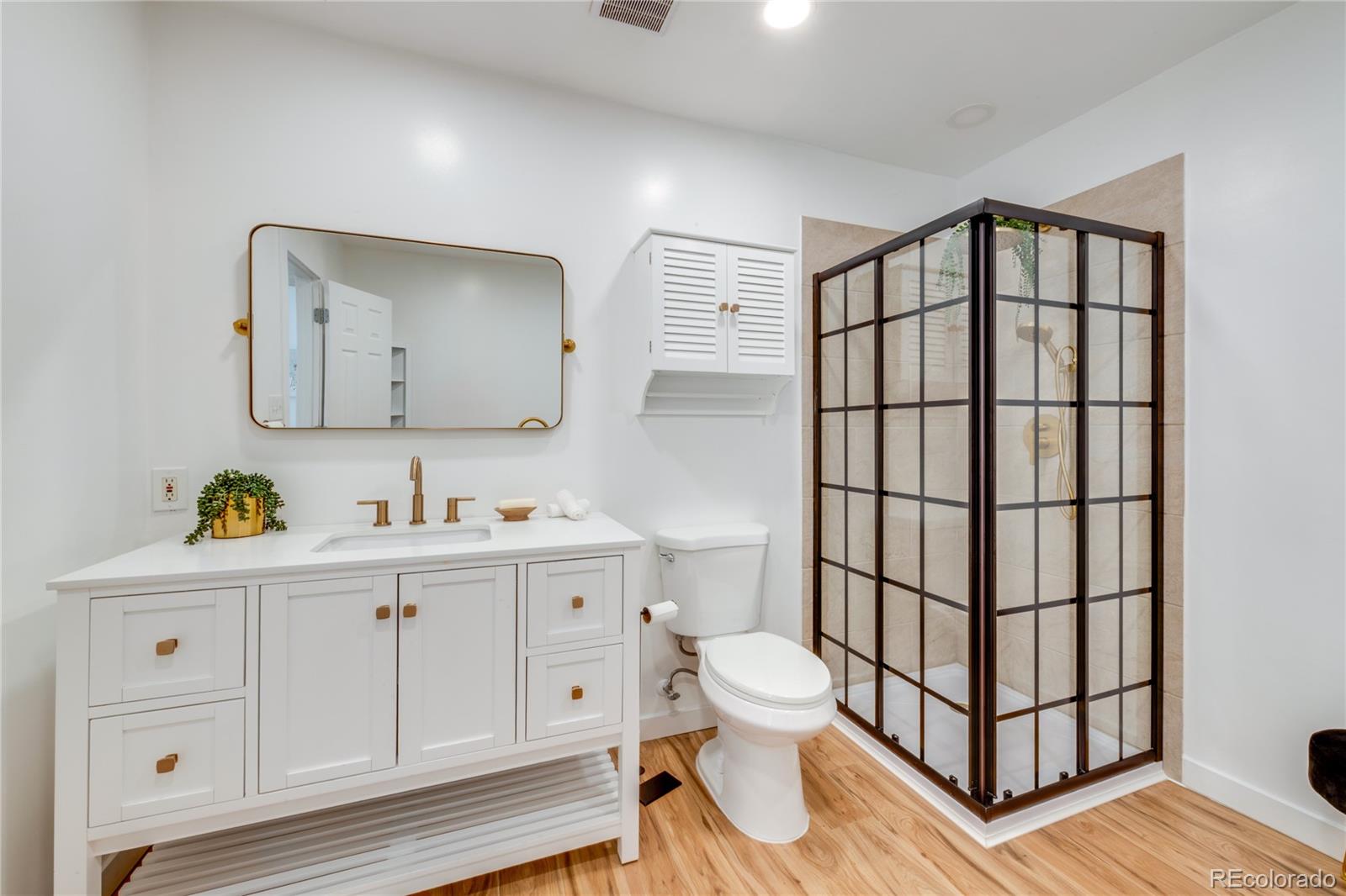 6811 West 48th Avenue Wheat Ridge, CO 80033 - Photo 11 of 33 a bathroom with a toilet a sink a vanity and mirror