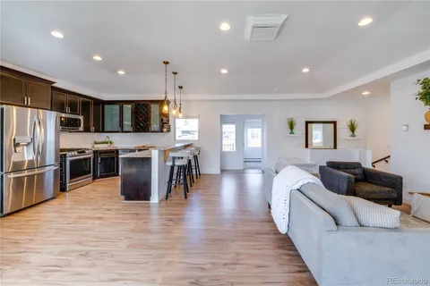 a living room with stainless steel appliances furniture wooden floor and a view of kitchen