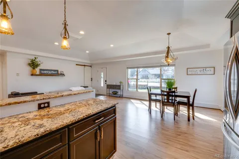 a view of a kitchen with granite countertop wooden floor and stainless steel appliances