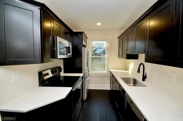 a kitchen with granite countertop a sink a stove and refrigerator