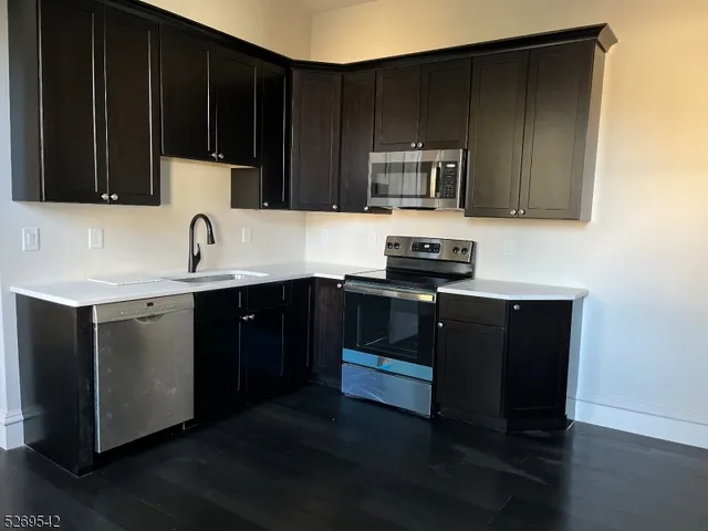 a kitchen with stainless steel appliances a sink a stove a microwave and wooden cabinets