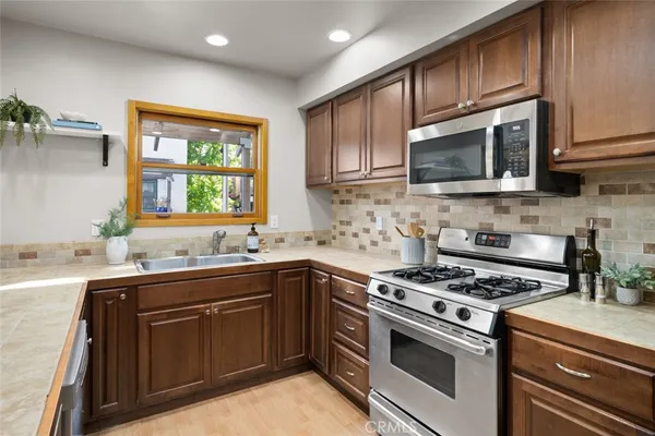 a kitchen with stainless steel appliances granite countertop a stove sink microwave and window
