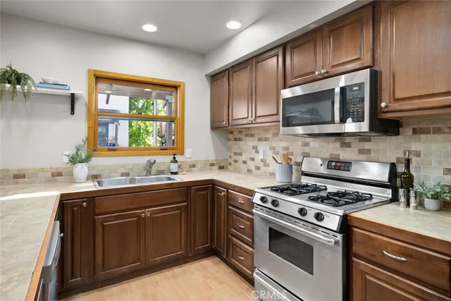 a kitchen with stainless steel appliances granite countertop a stove sink microwave and window
