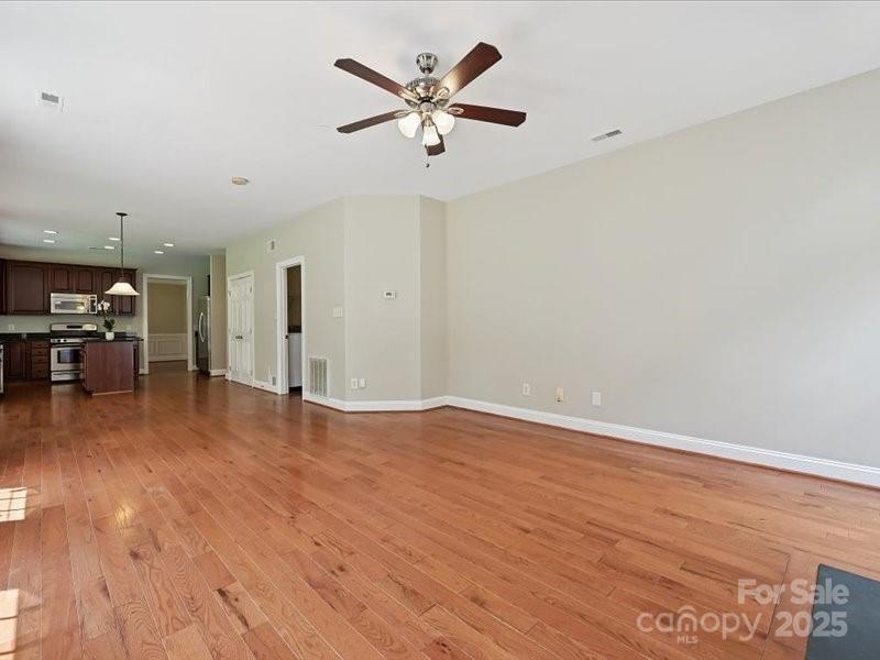 6932 Augustine Way Charlotte, NC 28270 - Photo 14 of 46 an empty room with wooden floor and a ceiling fan
