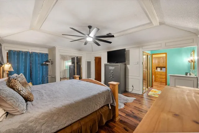 a spacious bedroom with a large bed a flat tv screen and dresser