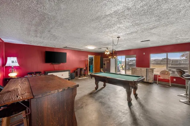 a living room with furniture pool table and large windows
