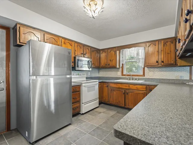 a kitchen with stainless steel appliances granite countertop a refrigerator and a sink