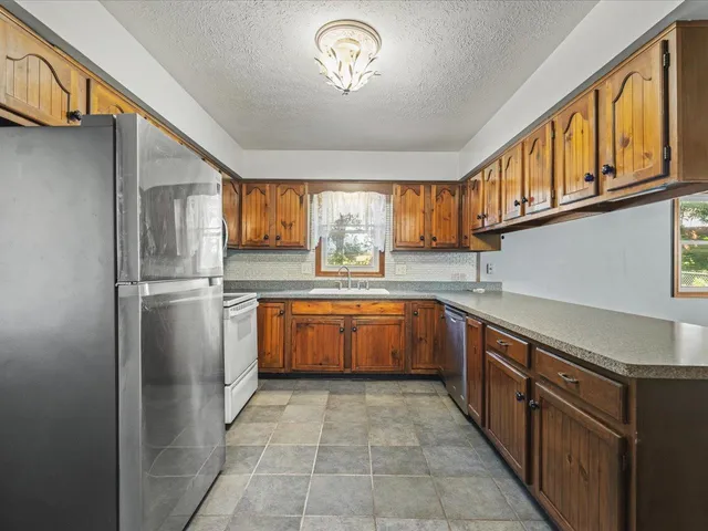 a kitchen with stainless steel appliances granite countertop a refrigerator and a sink