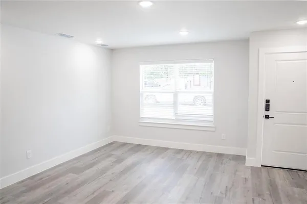 an empty room with wooden floor and windows