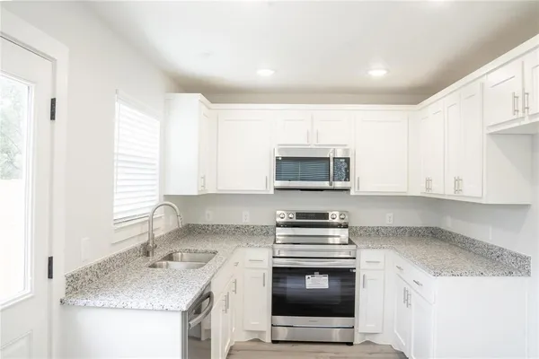 a kitchen with stainless steel appliances granite countertop a sink stove and microwave