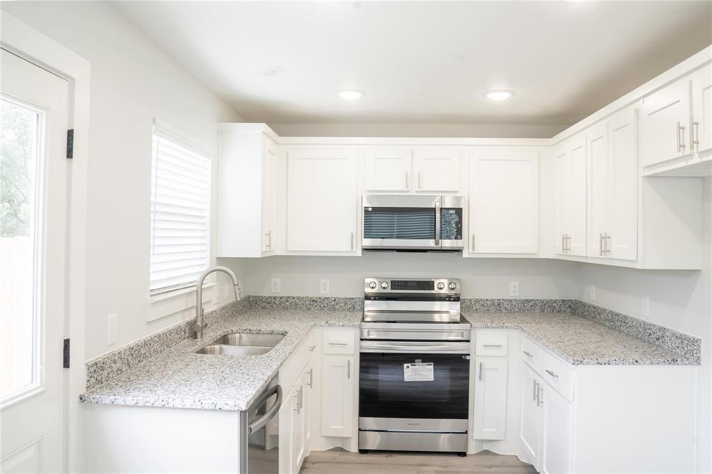 318 Henderson Street Bonham, TX 75418 - Photo 8 of 12 a kitchen with stainless steel appliances granite countertop a sink stove and microwave