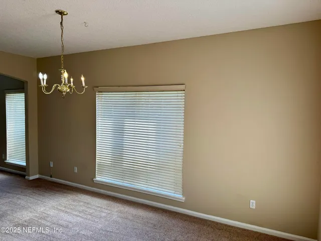 a view of a livingroom with a chandelier fire place and windows