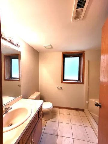a bathroom with a granite countertop sink a toilet and mirror